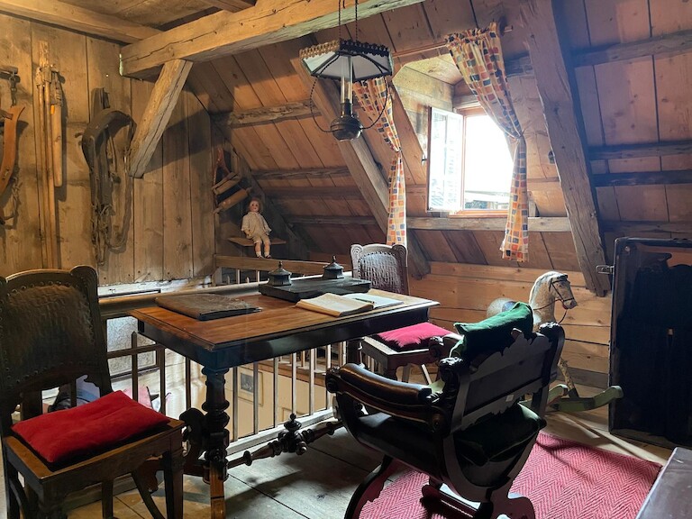Ein Raum unter dem Dach mit altem Schulpult, Schaukelpferd und Spielsachen – eine Mischung aus Arbeitszimmer und Kinderidyll vergangener Tage.