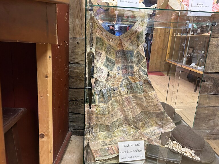 Das Fachingskleid einer Bad Brambacher, genäht aus Inflationsgeld, welches in einer Vitrine hängt.