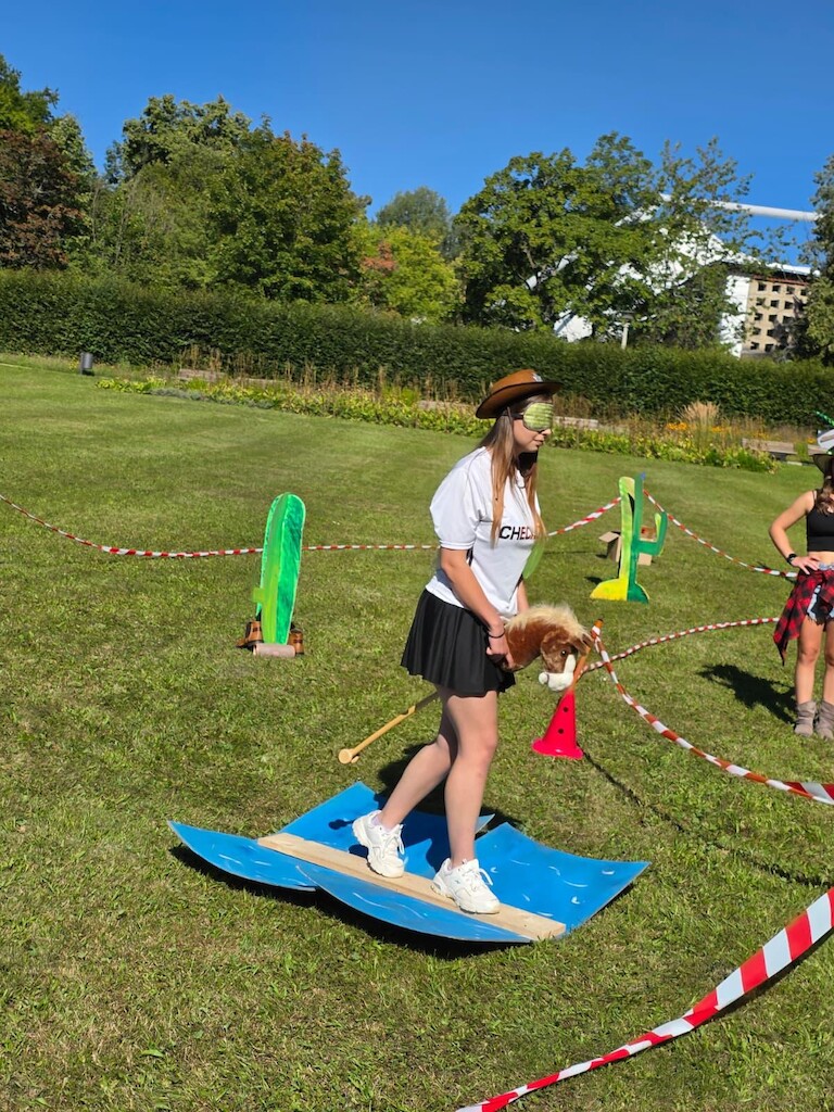 Mit Augenklappe auf einem Hobbyhorse über einen Steg.