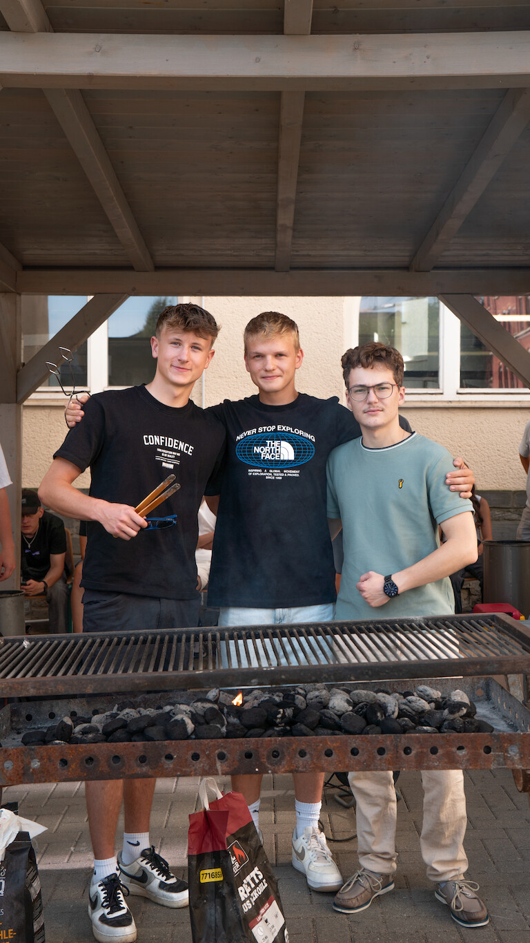 Drei Schüler der Beruflichen Gymnasiums hinter dem Grill.
