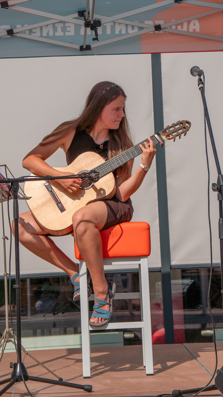 Eien Schülerin singt ein Lied mit ihrer Gitarre.