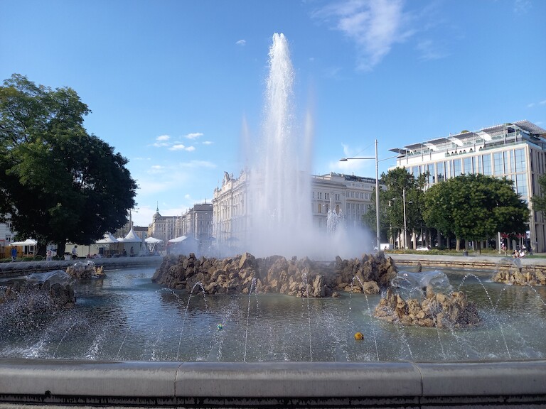 Der Hochstrahlbrunnen mit Wiener Gebäuden im Hintergrund.