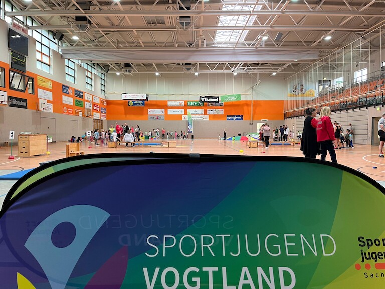 Das Schild Sporhjugend Vogtland verdeckt die halbe Turnhalle.