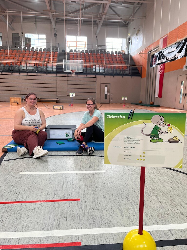Zwei Schüler sitzen bei der Station Zielwerfen.
