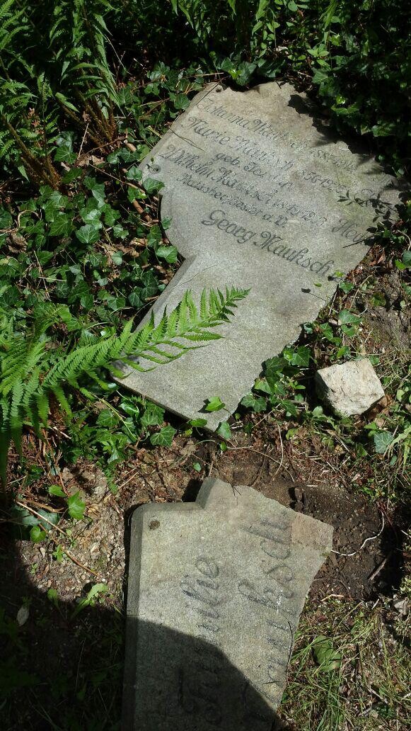 Zwei Bruchstücke in der Wiese. Auf einem ist die Aufschrift Georg Mauksch zu sehen.
