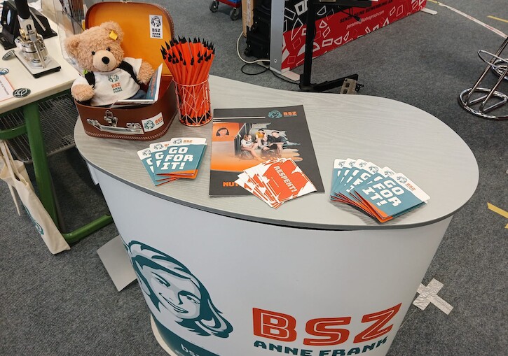 Unser Stand auf dem Berufsorientierungsmarkt mit Flyer, Stiften und dem Bär.