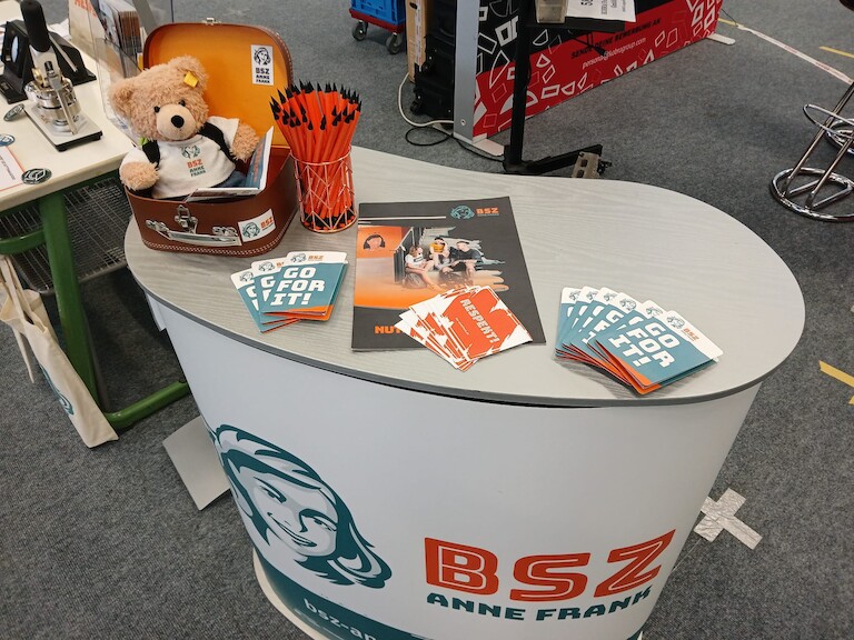 Unser Stand auf dem Berufsorientierungsmarkt mit Flyer, Stiften und dem Bär.