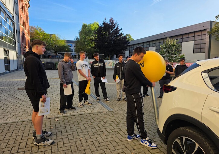 Die Schüler beobachten wieviel Abgase in den Luftballons eingeblasen werden.