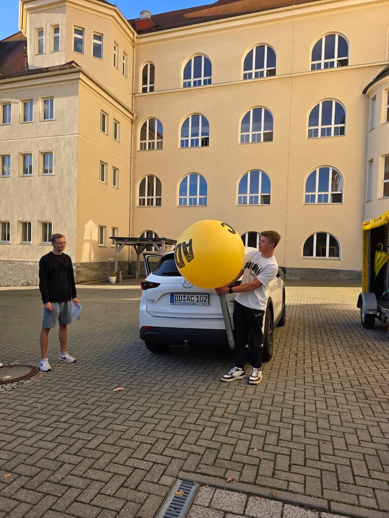 Ein Schüler befüllt den Luftballon mit CO2 aus dem Auspuff.