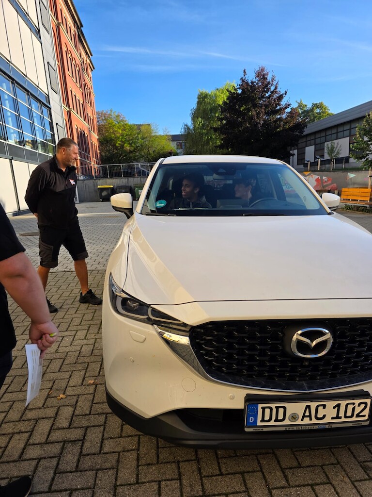 Schüler sitzen im Auto und machen den Hörtest.