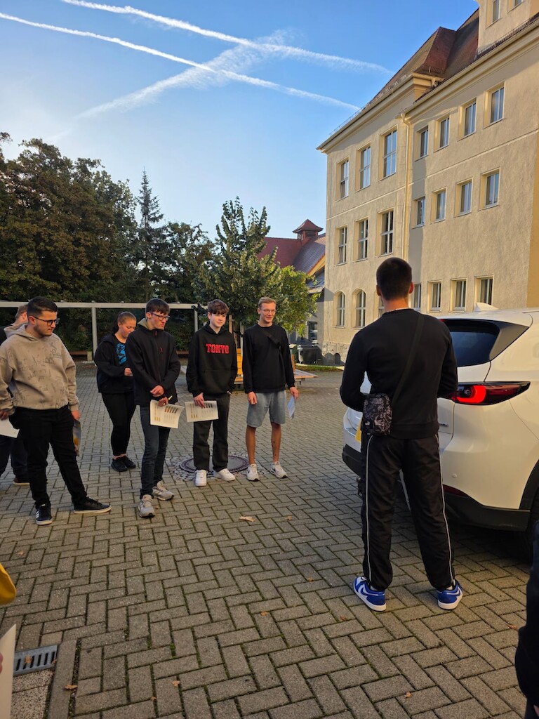 Die Schüler stehen um das Auto herum.