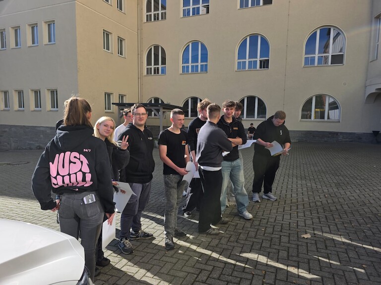 Die Schülerinnen und Schüler stehen in einer Reihe.