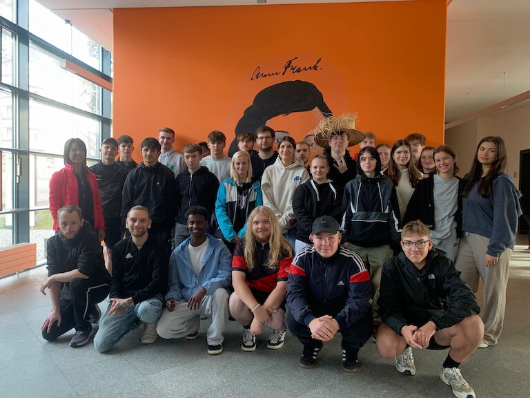 Die EH25b posiert mit ihrer Lehrerin auf einem Gruppenbild.