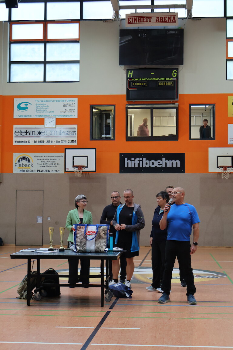 Ein Lehrer verkündet sich Siegerinnen und Sieger der Wettbewerbe. Das restliche Sportlehrerteam hinter ihm.