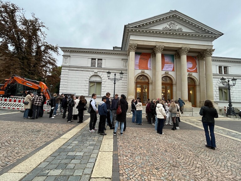Die Schülerinnen und Schüler warten vor dem Eingang des Theaters.