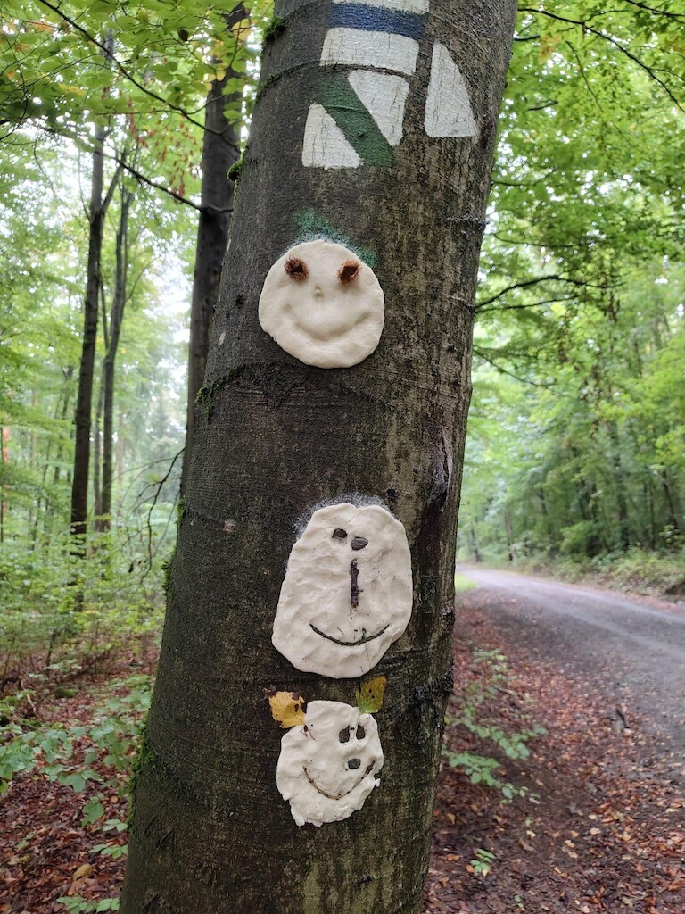 Mehrere Salzteiggesichter hängen übereinander am Baum.