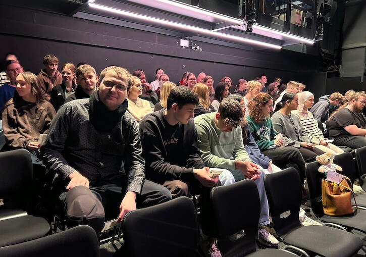Die Schülerinnen und Schüler warten auf den Beginn des Theaterstücks.