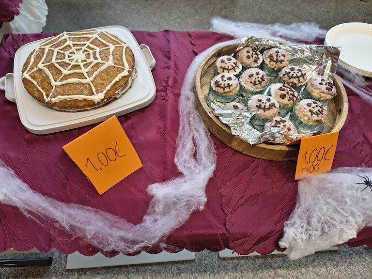 Eine Torte mit Spinnennetz und Muffins mit Fledermäusen darauf werden zum Verkauf angeboten.