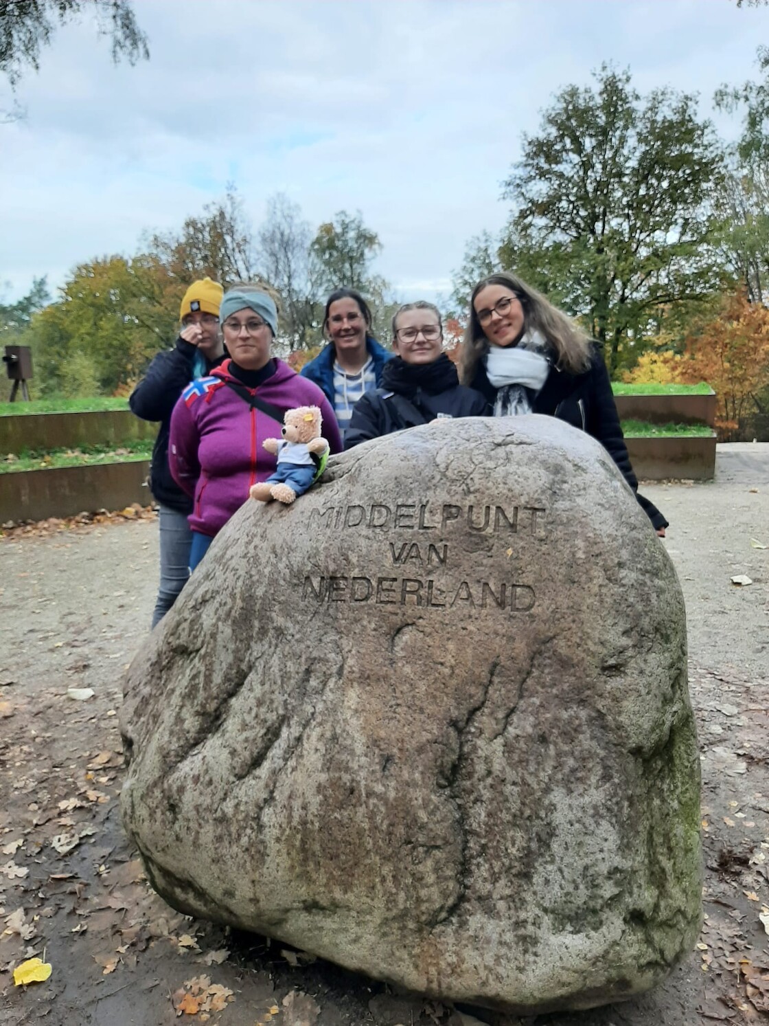 Fünf Schülerinnen stehen hinter dem Stein Mittelpunkt der Niederlande.