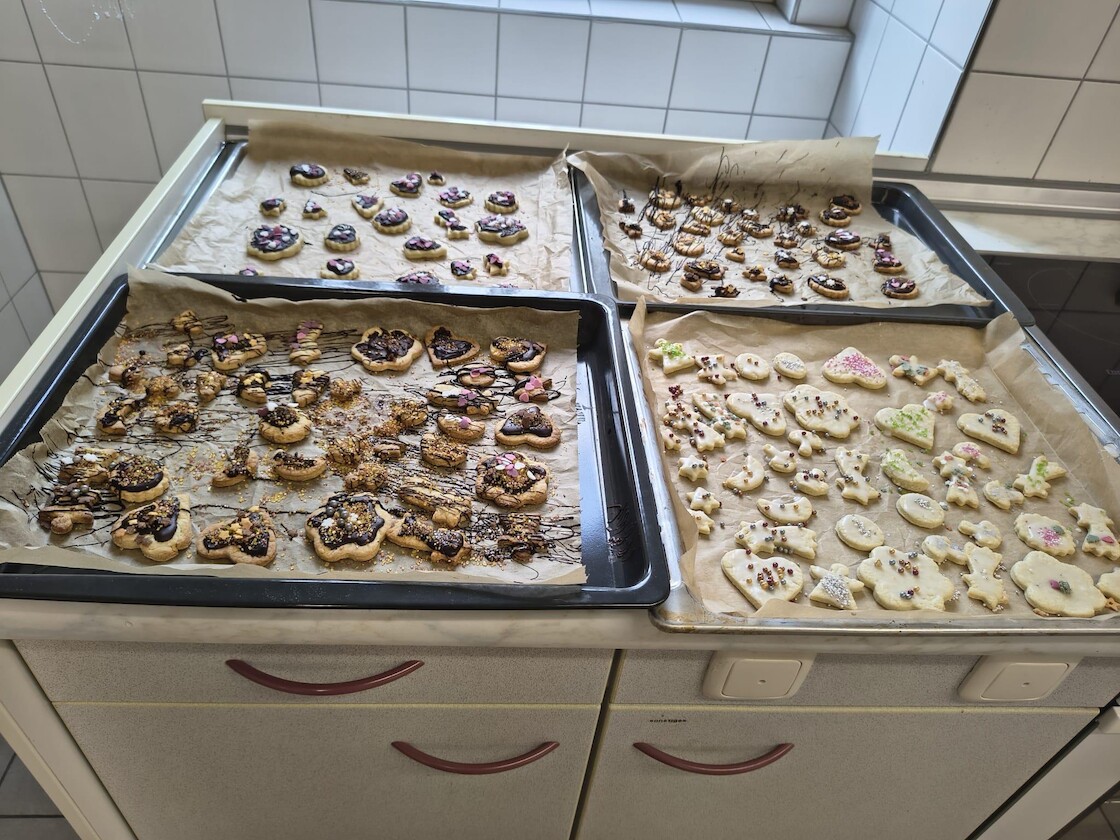 Vier Bleche fertige Plätzchen.