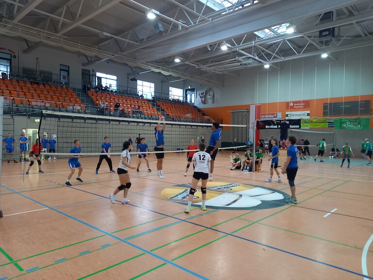 Zwei Mannschaften beim Volleyball spielen.