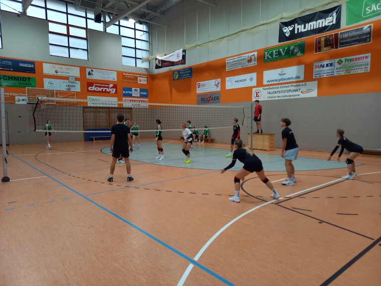 Zwei Mannschaften beim Volleyball spielen.
