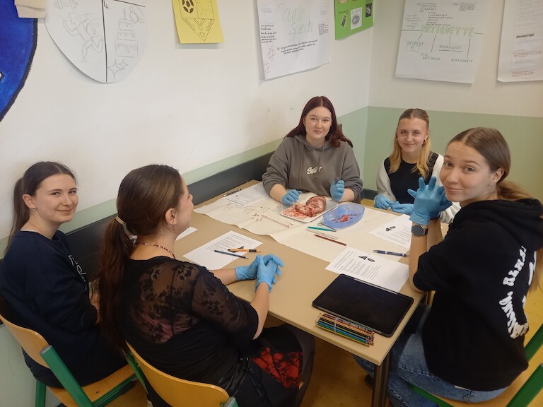 Fünf Schülerinnen am Tisch mit ihrem Herz.