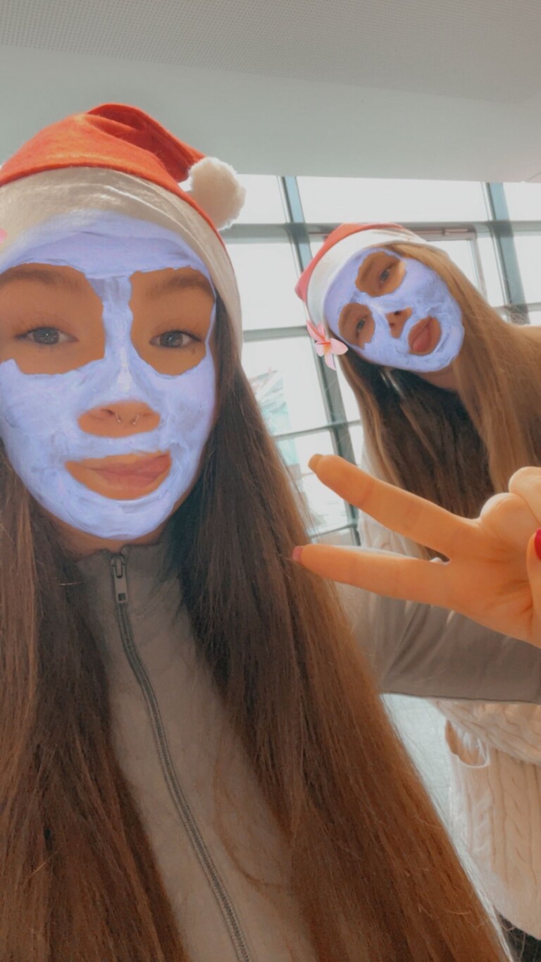 Zwei Schülerinnen mit weißen Masken und Weihnachtsmützen.