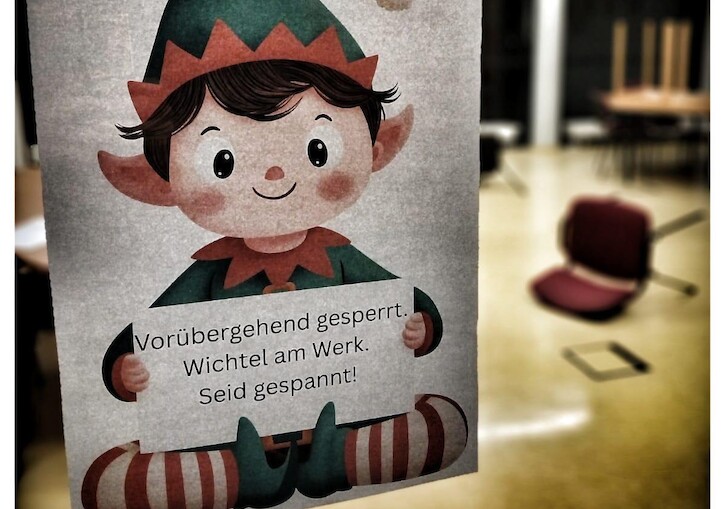 Der Wichel hält ein Schild hoch mit: 