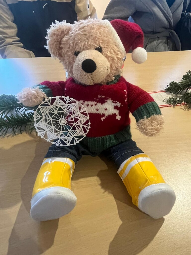 Unser Bär hätl eine Stickerei in der Hand.