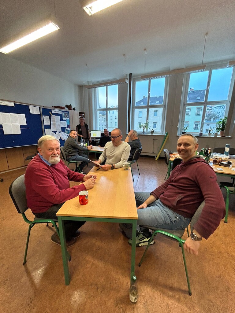 Die Spieler am Tisch schauen in die Kamera.