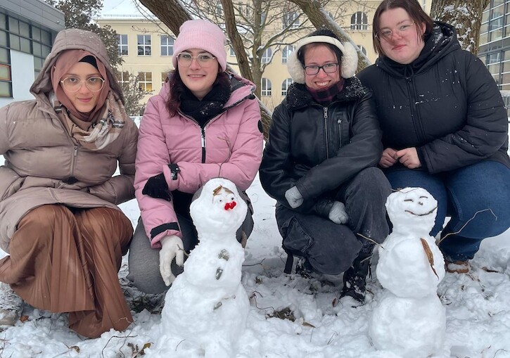 Vier Schülerinnen posieren hinten den gebauten Schneemännern.