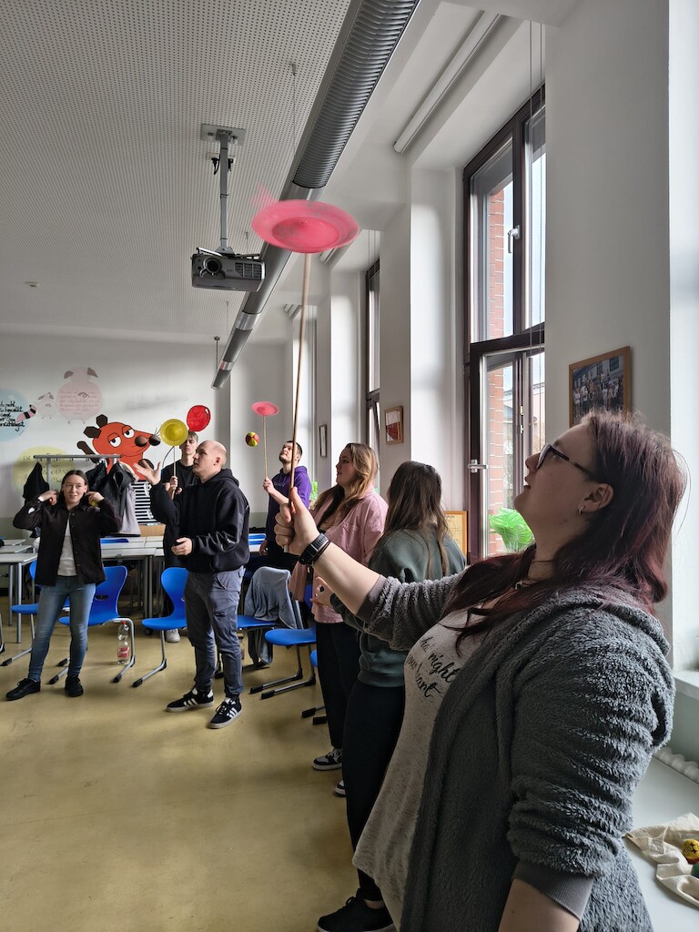 Die EZ Schüler balancieren Teller auf Stäben.