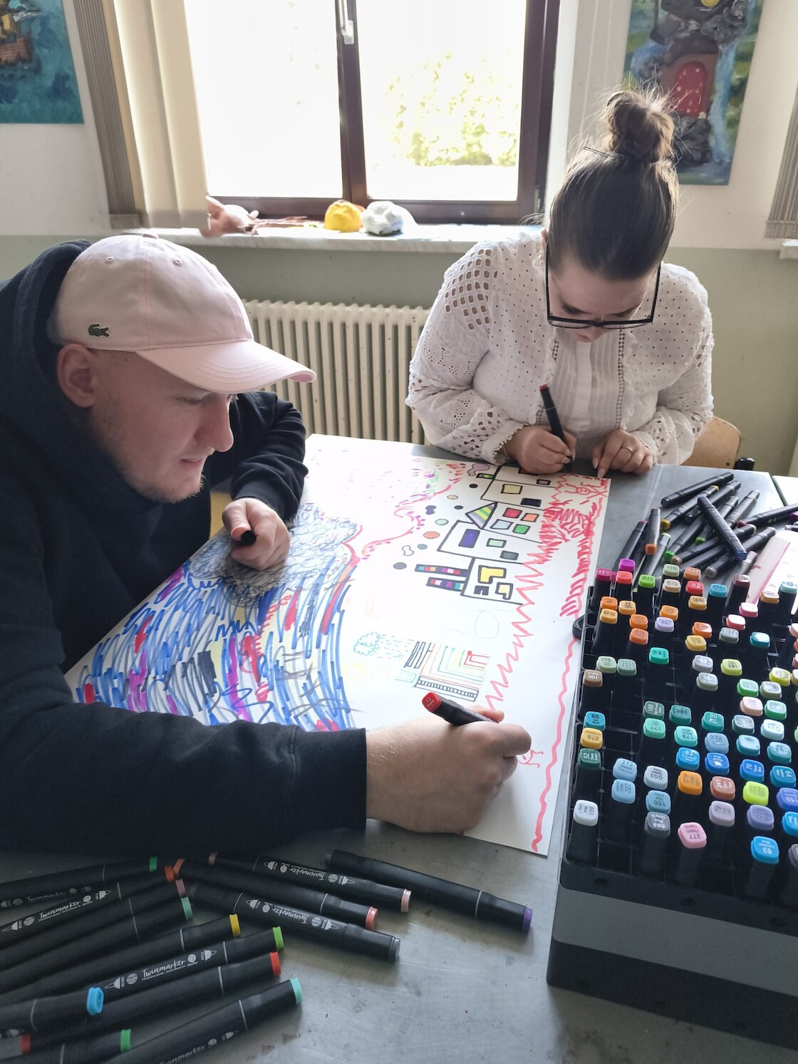 Zwei Schüler gestalten das Bild in bunten Farben.