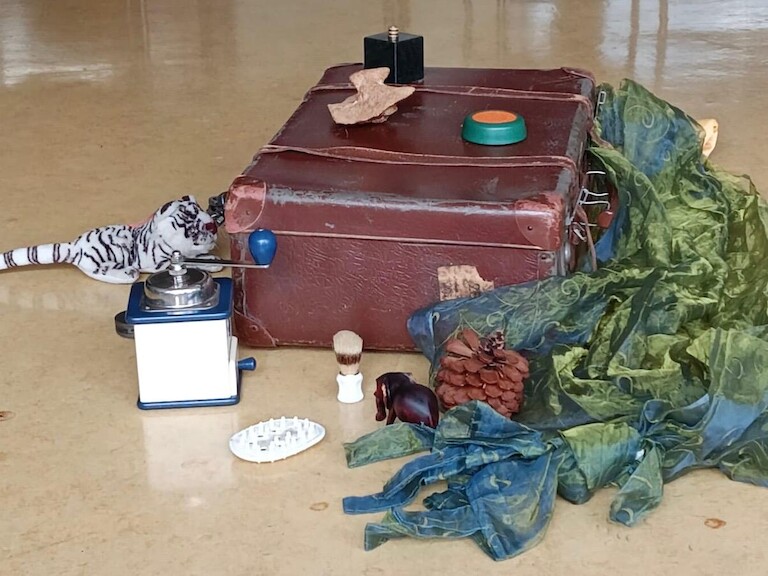 Materialien liegen auf dem Boden - ein Koffer und Tücher.