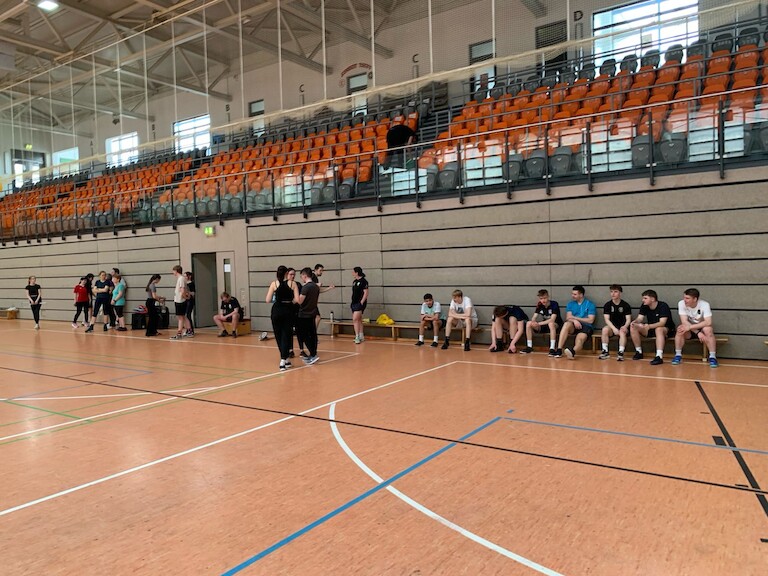 Die Teilnehmer sitzen auf Bänken in der Halle.