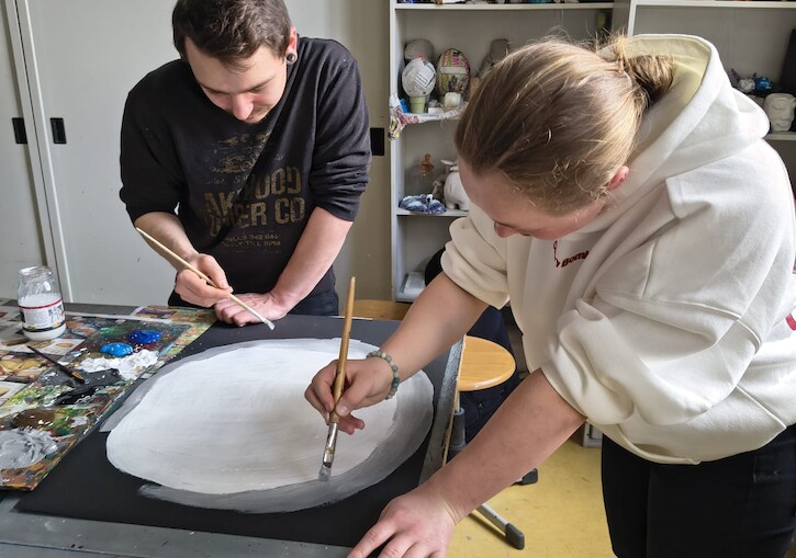 Zwei Schüler malen ein Bild.