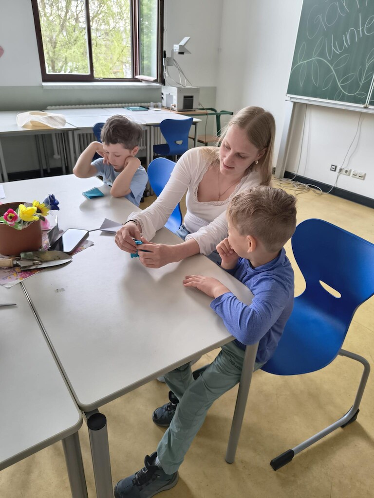 Eine Erzieherin und zwei Kinder am Tisch.