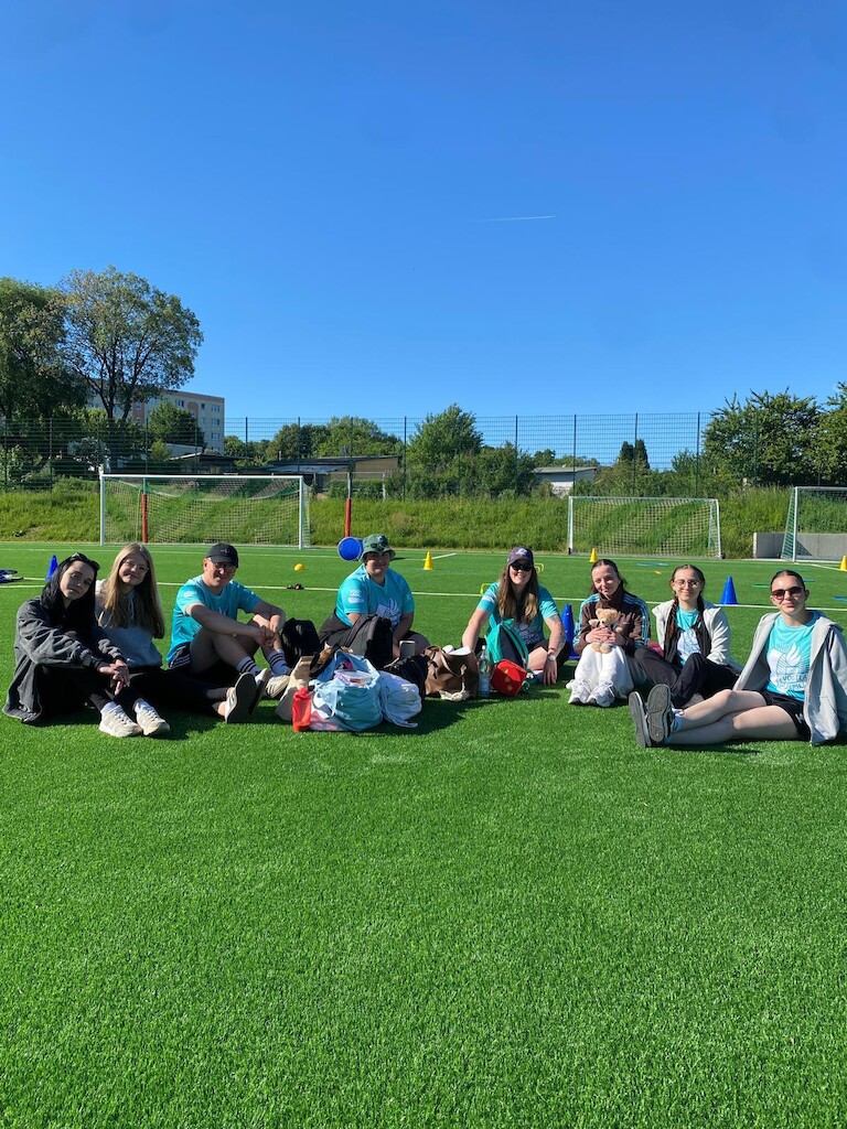 Die Schülerinnen und Schüler sitzen gemütlich auf dem Rasen.