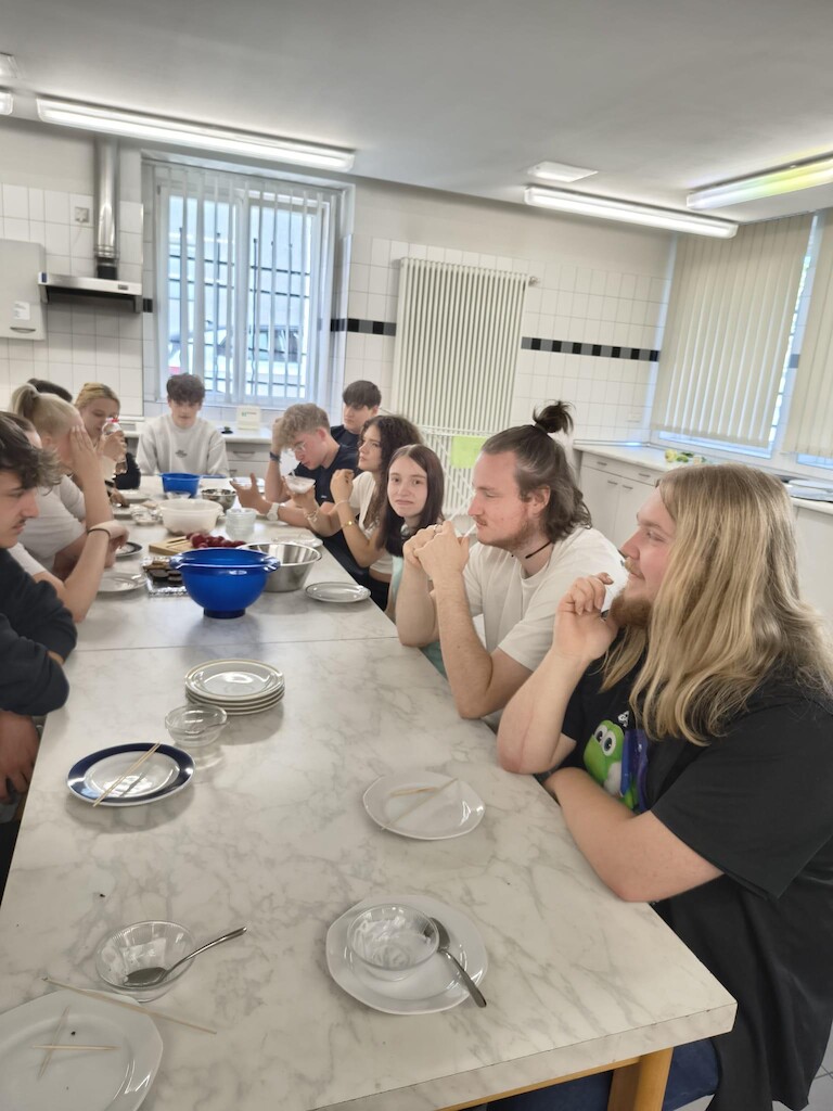 Schülerinnen und Schüler sitzen am Tisch