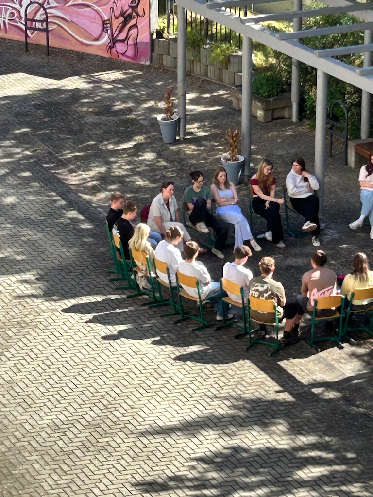 Die Schüler sitzen im Sitzkreis auf dem Schuhof
