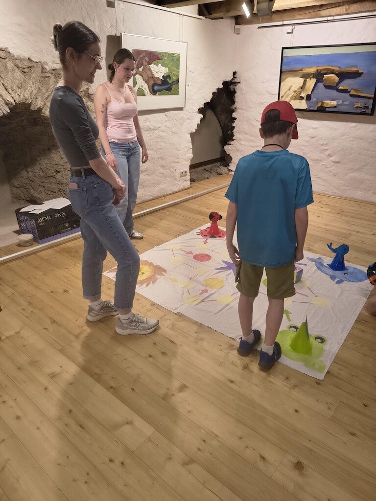 Zwei Schülerinnen und eine Kind stehen am Spielfeld