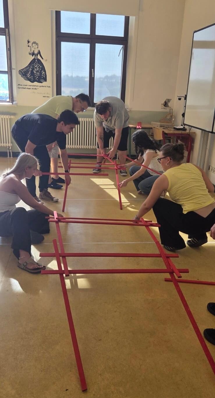 Schülerinnen und Schüler bauen eine Brücke aus Holzstäben
