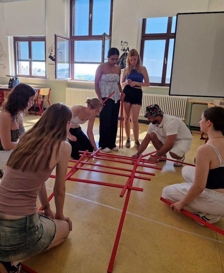 Schülerinnen und Schüler bauen eine Brücke aus Holzstäben