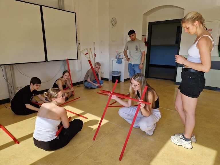 Schülerinnen und Schüler bauen eine Brücke aus Holzstäben