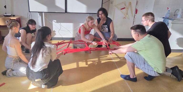 Schülerinnen und Schüler bauen eine Brücke aus Holzstäben