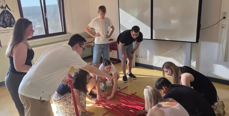 Schülerinnen und Schüler bauen eine Brücke aus Holzstäben