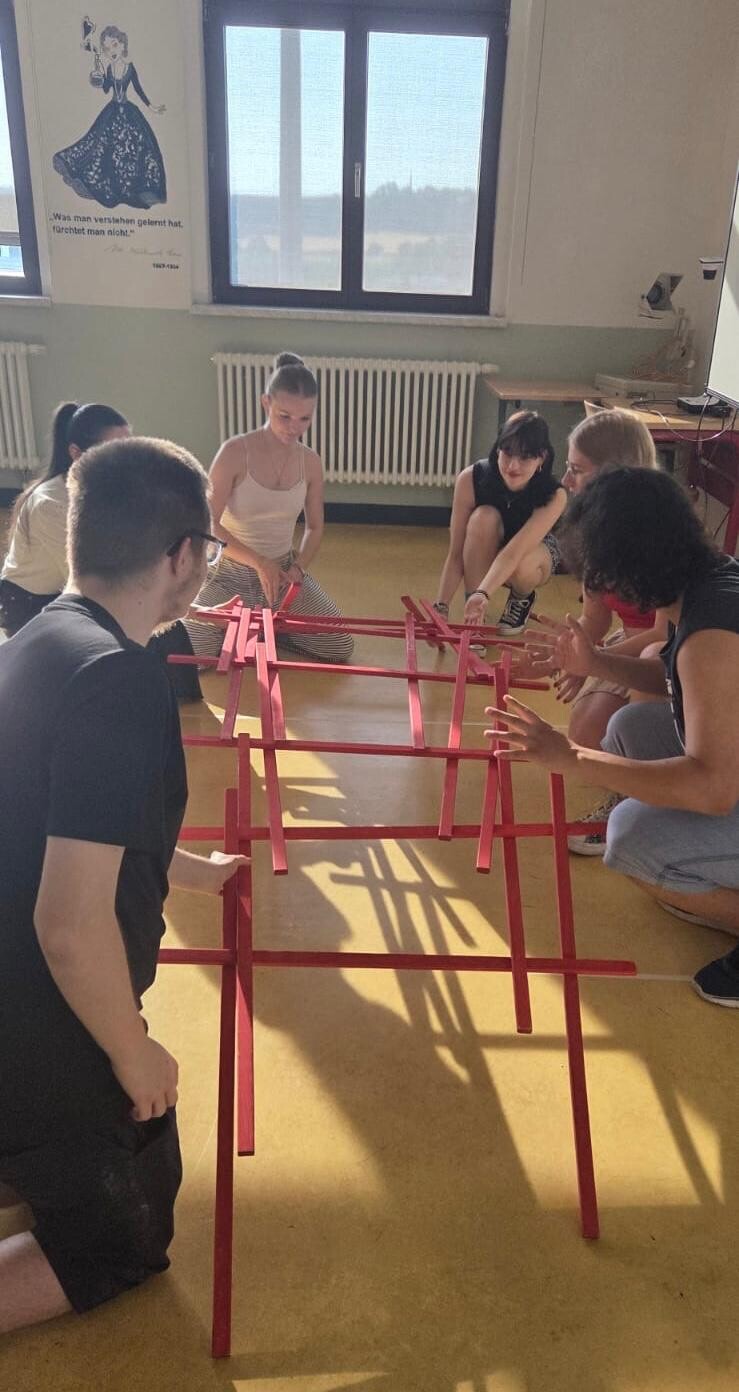 Schülerinnen und Schüler bauen eine Brücke aus Holzstäben