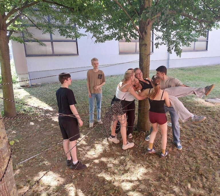Die Schüler heben einen anderen Mitschüler durch das Spinnennetz.